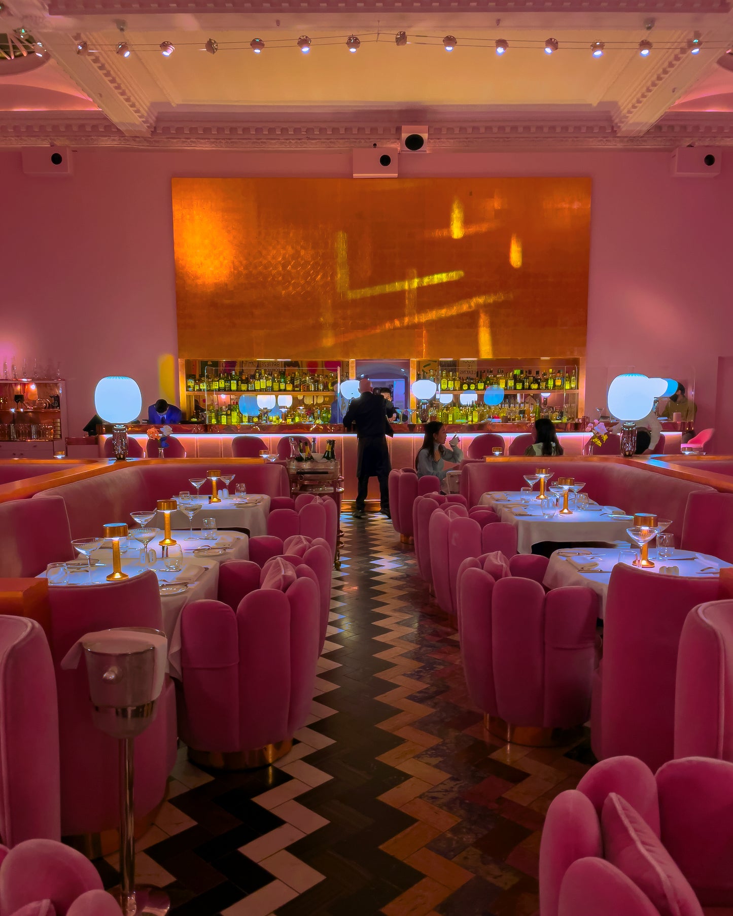 Pink-themed restaurant interior with tables and chairs, bar area, and decorative elements.