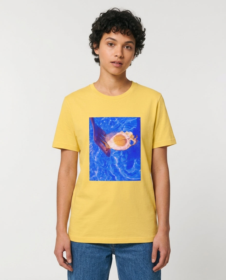 Person wearing a yellow t-shirt with a graphic design on a plain background