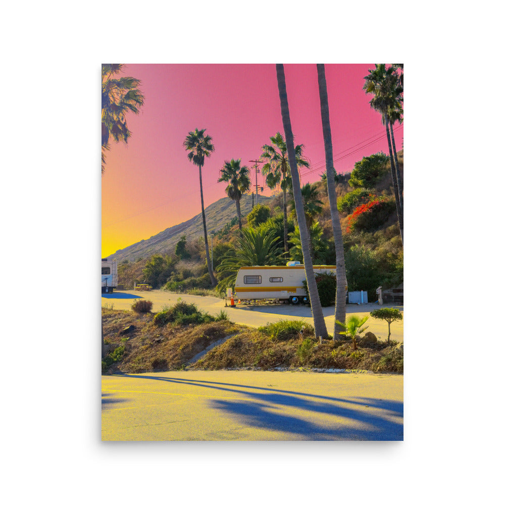 Scenic view with palm trees, a mountain, and a trailer under a pink sky.