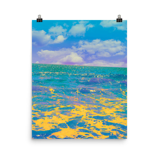 Surreal fine art ocean photograph with vivid teal and turquoise waves in the distance, transitioning to swirling pools of golden yellow and deep indigo in the foreground, beneath a lavender-blue sky with soft white clouds