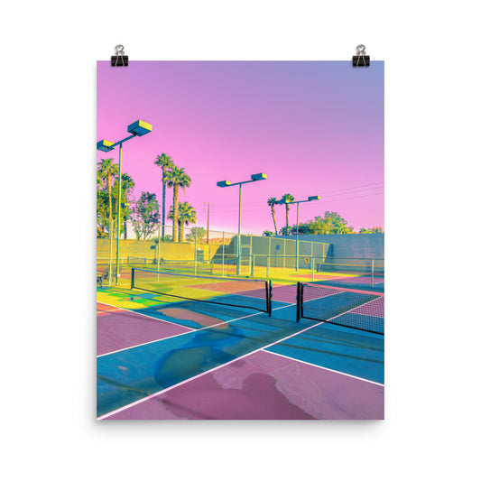 Unframed fine art photography print of a sun-drenched tennis court in pink, lilac and sky blue, with palm trees and floodlights against a glowing magenta sky, retro vaporwave aesthetic, bold colourful wall art for living room or games room