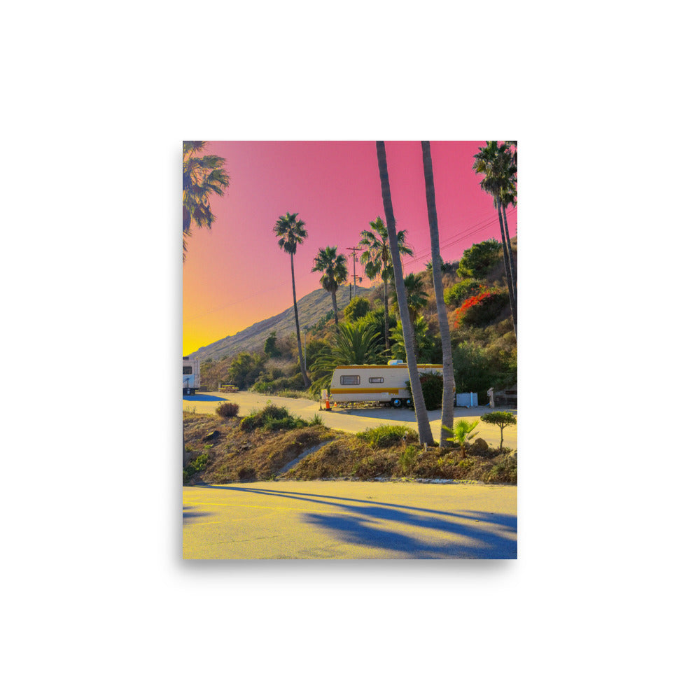 Vintage trailer parked among palm trees with a pink sky