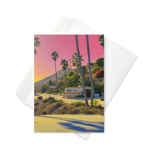 Card with a scenic view of palm trees and a camper van, featuring a pink sky.
