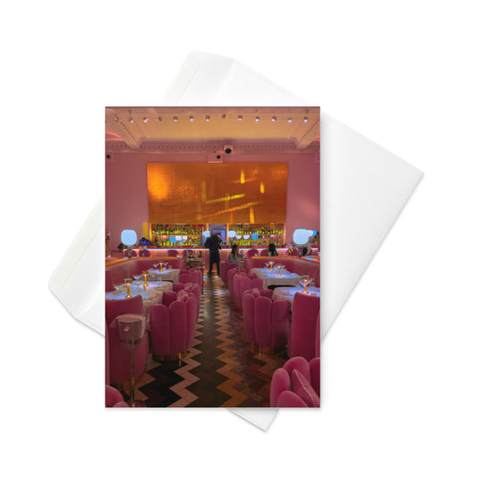 Pink interior of a restaurant with tables and chairs, featuring a bar area.