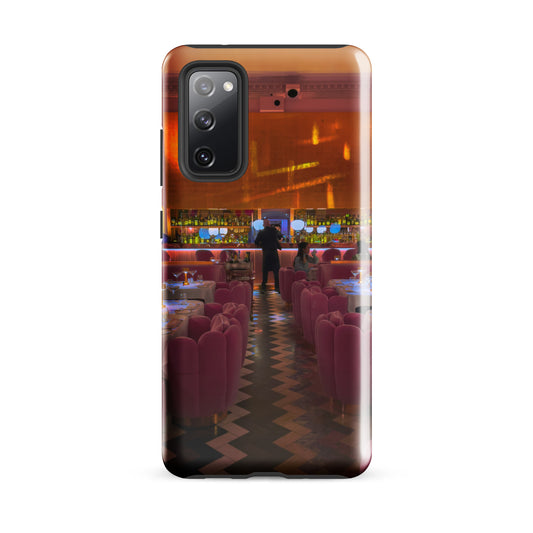 Phone case with a design of a restaurant interior with pink chairs and a cityscape in the background.